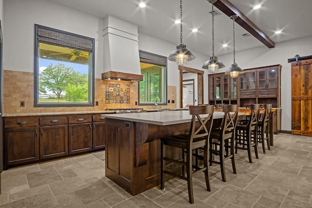 101 Goldfinch Ln, Weatherford, TX 76088 - kitchen featuring a barn door, custom exhaust hood, tasteful backsplash, light countertops, and a breakfast bar area
