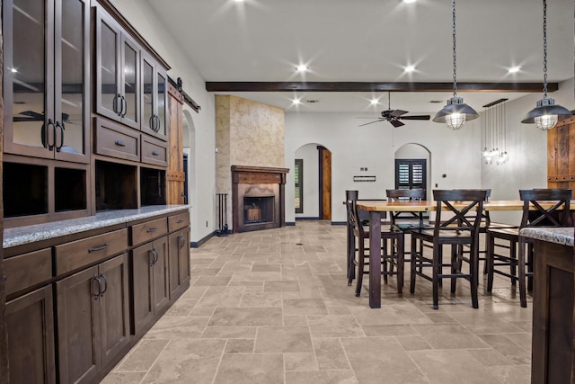 101 Goldfinch Ln, Weatherford, TX 76088 - dining room featuring arched walkways, ceiling fan, a large fireplace, beam ceiling, and light stone finish flooring