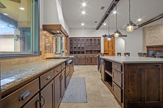 101 Goldfinch Ln, Weatherford, TX 76088 - kitchen featuring premium range hood, hanging light fixtures, dark brown cabinets, backsplash, and light stone finish flooring