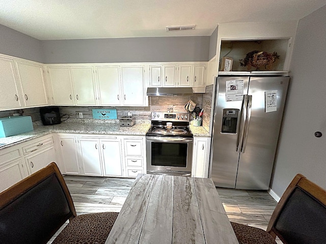 1325 W Chestnut St, Denison, TX 75020 - kitchen with stainless steel appliances, under cabinet range hood, light wood-style flooring, tasteful backsplash, and white cabinetry