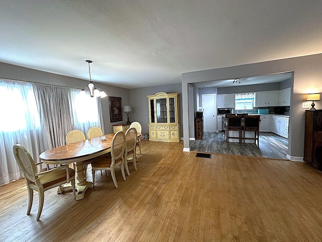 1325 W Chestnut St, Denison, TX 75020 - dining area featuring a chandelier, wood-type flooring, and a textured ceiling