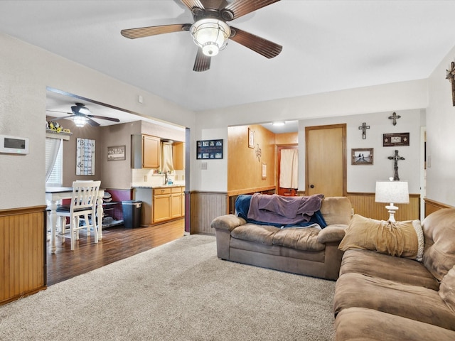 2012 Mobile Dr, Ennis, TX 75119 - carpeted living room featuring a wainscoted wall, ceiling fan, and wooden walls
