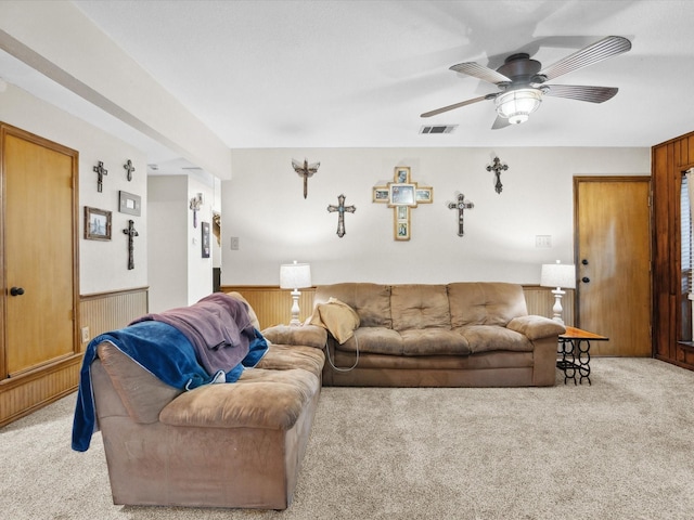 2012 Mobile Dr, Ennis, TX 75119 - living room featuring light colored carpet, wainscoting, wooden walls, and a ceiling fan