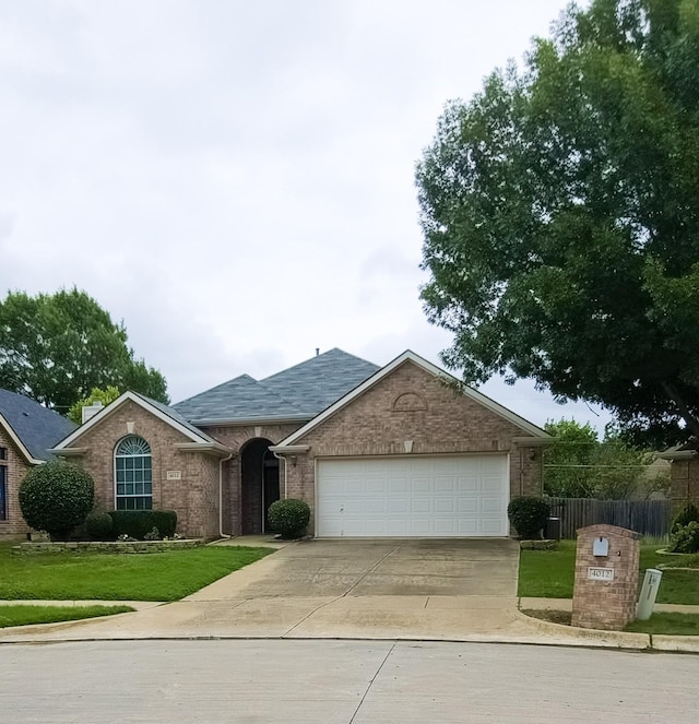 4012 Glenwyck Dr E, North Richland Hills, TX 76180 - view of front of house featuring driveway, a garage, brick siding, and roof with shingles