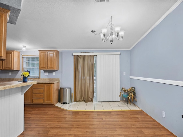 403 SE County Road 3048c, Corsicana, TX 75109 - kitchen with ornamental molding, a chandelier, light wood-style floors, light countertops, and brown cabinets