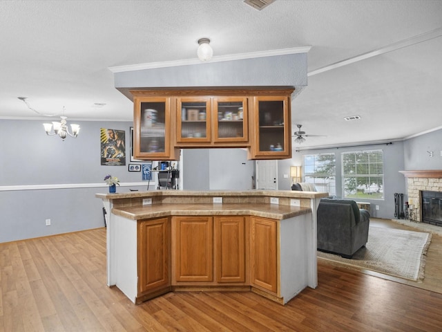 403 SE County Road 3048c, Corsicana, TX 75109 - kitchen featuring light wood-type flooring, open floor plan, brown cabinets, ornamental molding, and a textured ceiling