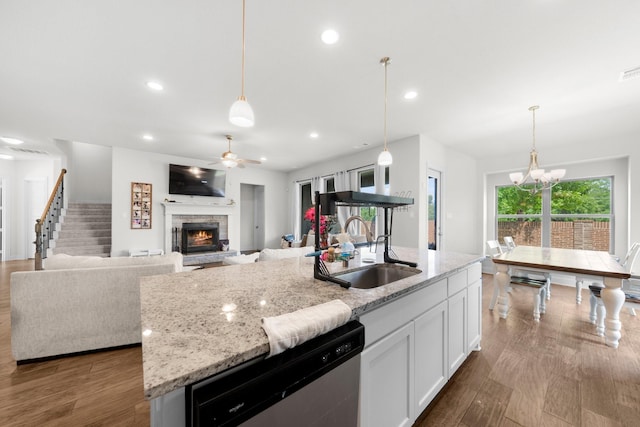 406 Garden Tree Trl, Midlothian, TX 76065 - kitchen featuring stainless steel dishwasher, a stone fireplace, ceiling fan, white cabinets, and light stone counters