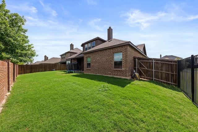 406 Garden Tree Trl, Midlothian, TX 76065 - rear view of house with a trampoline, brick siding, a fenced backyard, roof with shingles, and a chimney