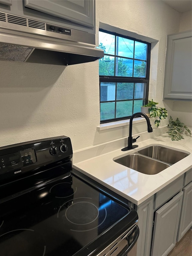 616 Leyenda Dr, Mesquite, TX 75149 - kitchen featuring black range with electric stovetop, under cabinet range hood, light countertops, a textured wall, and gray cabinets