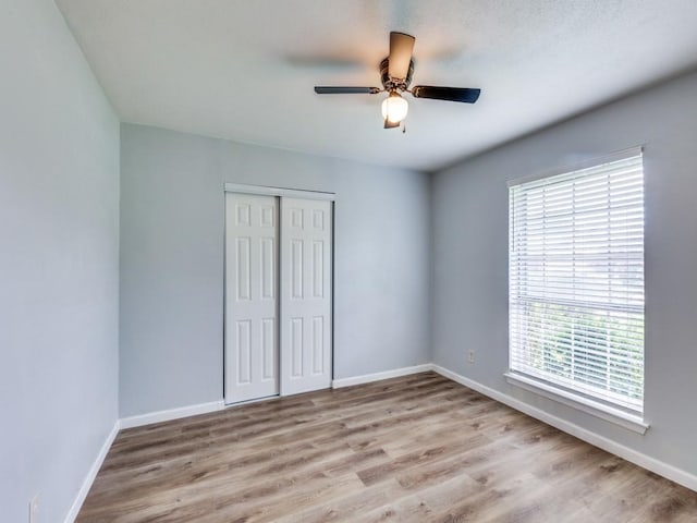 810 Serenade Ln, Richardson, TX 75081 - unfurnished bedroom featuring multiple windows, a closet, and wood finished floors