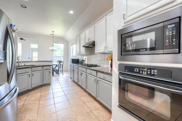2860 Prado, Grand Prairie, TX 75054 - kitchen with stainless steel appliances, under cabinet range hood, backsplash, vaulted ceiling, and gray cabinetry