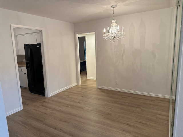 6036 Birchbrook Dr Unit 127, Dallas, TX 75206 - unfurnished dining area with wood finished floors and a chandelier