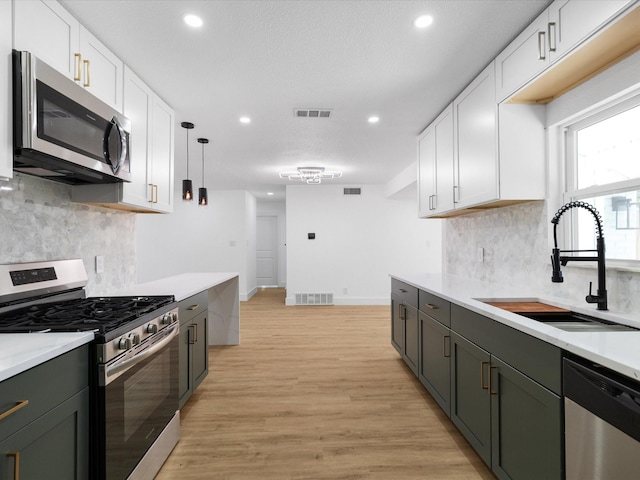 1910 Durham St, Irving, TX 75062 - kitchen featuring appliances with stainless steel finishes, white cabinets, light countertops, recessed lighting, and backsplash