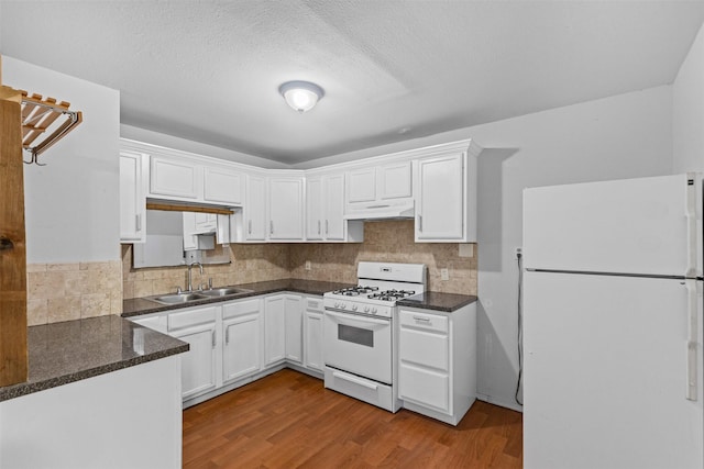 504 Cozby St N, Benbrook, TX 76126 - kitchen with white appliances, dark countertops, under cabinet range hood, white cabinetry, and a textured ceiling