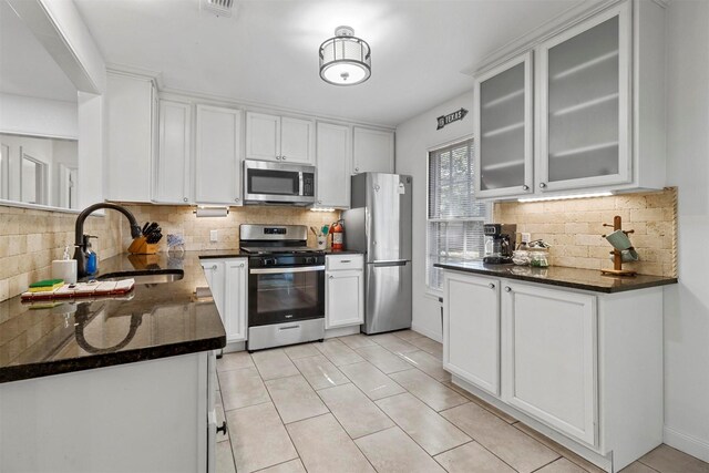 717 Thersa Dr, River Oaks, TX 76114 - kitchen with stainless steel appliances, tasteful backsplash, white cabinetry, and glass insert cabinets