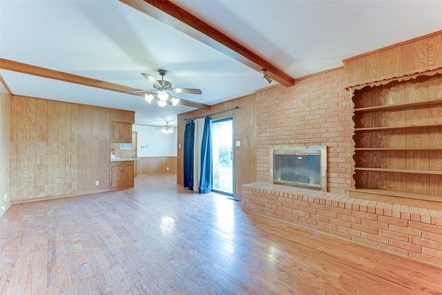 410 Ovilla Rd, Waxahachie, TX 75167 - unfurnished living room featuring wood walls, ceiling fan, beam ceiling, a fireplace, and wood finished floors