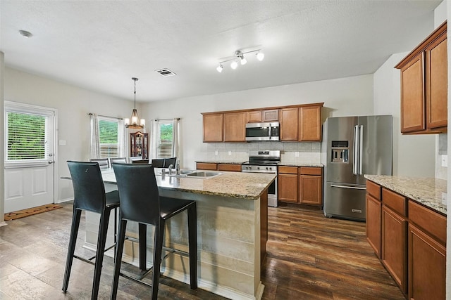 1209 Jasper Xing, Princeton, TX 75407 - kitchen featuring stainless steel appliances, brown cabinets, a chandelier, and plenty of natural light