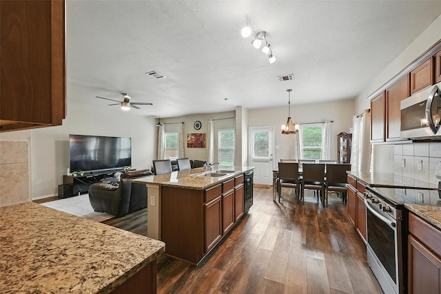 1209 Jasper Xing, Princeton, TX 75407 - kitchen featuring appliances with stainless steel finishes, dark wood-style flooring, plenty of natural light, a ceiling fan, and a textured ceiling