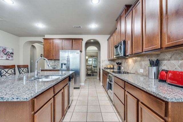 3820 Buchanan St, Mckinney, TX 75071 - kitchen with stainless steel appliances, arched walkways, light tile patterned floors, a center island with sink, and recessed lighting