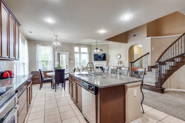 3820 Buchanan St, Mckinney, TX 75071 - kitchen featuring stainless steel appliances, a fireplace, light tile patterned floors, ceiling fan, and a breakfast bar