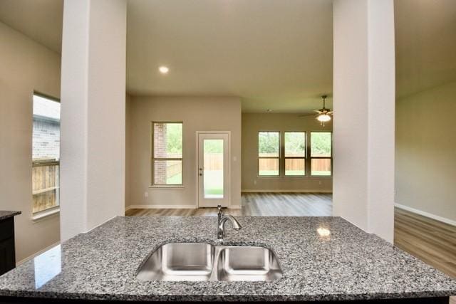 2609 Donella Dr, Denton, TX 76207 - kitchen featuring wood finished floors, light stone counters, ceiling fan, an island with sink, and recessed lighting
