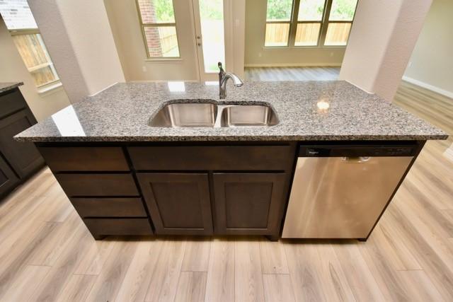 2609 Donella Dr, Denton, TX 76207 - kitchen featuring dishwasher, dark brown cabinetry, light wood-type flooring, light stone countertops, and plenty of natural light