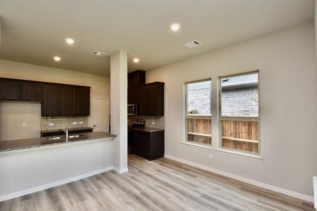 2609 Donella Dr, Denton, TX 76207 - kitchen featuring tasteful backsplash, light wood-style flooring, dark brown cabinetry, recessed lighting, and stainless steel microwave