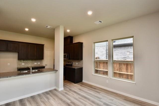 2609 Donella Dr, Denton, TX 76207 - kitchen featuring decorative backsplash, light wood-style floors, dark brown cabinets, recessed lighting, and stainless steel microwave