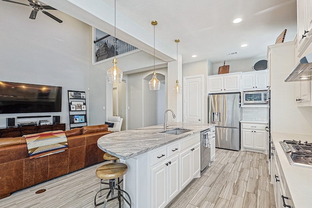 1701 Trinidad Way, Argyle, TX 76226 - kitchen with appliances with stainless steel finishes, wood tiled floors, white cabinets, open floor plan, and a breakfast bar area