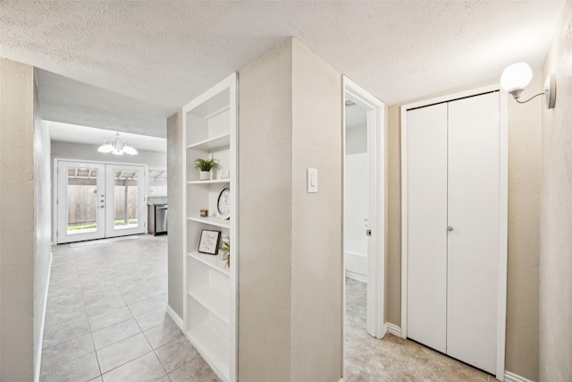 5109 Bartlett Dr, The Colony, TX 75056 - hall featuring a textured ceiling, light tile patterned floors, built in shelves, and a chandelier