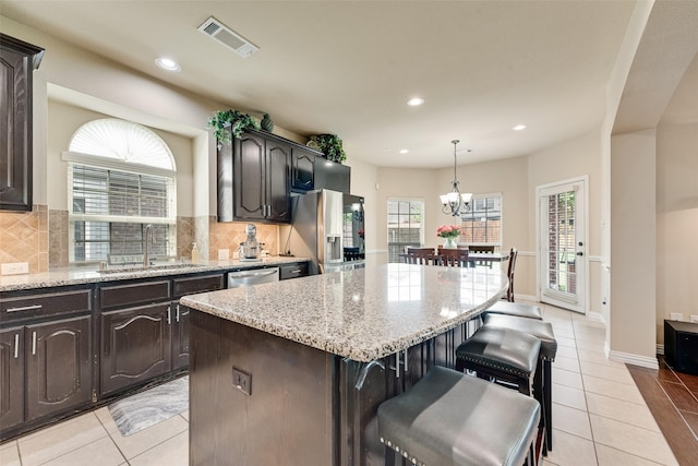 1220 Glendon Dr, Forney, TX 75126 - kitchen with a breakfast bar area, appliances with stainless steel finishes, decorative backsplash, a kitchen island, and a chandelier