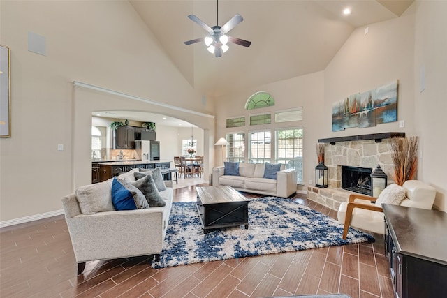 1220 Glendon Dr, Forney, TX 75126 - living room with arched walkways, high vaulted ceiling, a ceiling fan, wood finished floors, and a stone fireplace