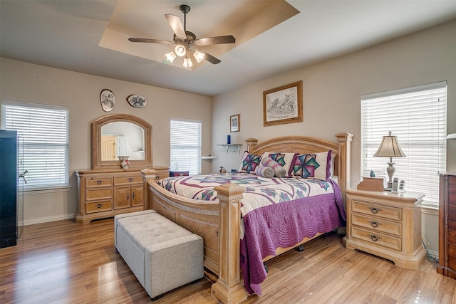 2536 Glenn Ranch Dr, Burleson, TX 76028 - bedroom with multiple windows, light wood-style floors, a tray ceiling, and a ceiling fan