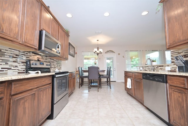 3209 Silver Point Ct, Mansfield, TX 76063 - kitchen featuring stainless steel appliances, decorative backsplash, a chandelier, recessed lighting, and brown cabinets