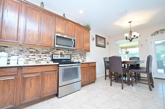 3209 Silver Point Ct, Mansfield, TX 76063 - kitchen featuring stainless steel appliances, a chandelier, backsplash, brown cabinetry, and recessed lighting