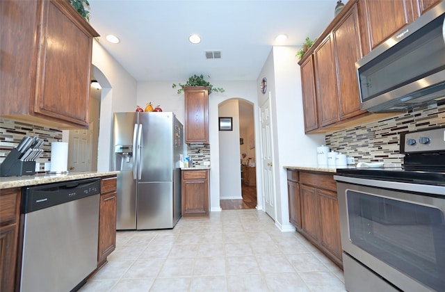 3209 Silver Point Ct, Mansfield, TX 76063 - kitchen with stainless steel appliances, backsplash, arched walkways, light tile patterned flooring, and recessed lighting