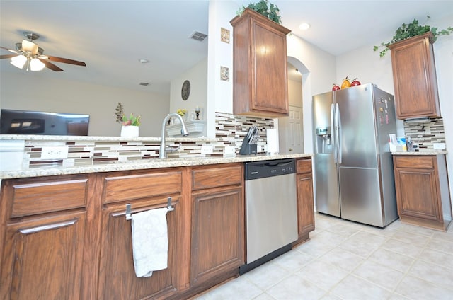 3209 Silver Point Ct, Mansfield, TX 76063 - kitchen featuring appliances with stainless steel finishes, backsplash, a ceiling fan, brown cabinets, and light tile patterned floors