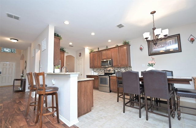 3209 Silver Point Ct, Mansfield, TX 76063 - kitchen with stainless steel appliances, arched walkways, a peninsula, backsplash, and recessed lighting