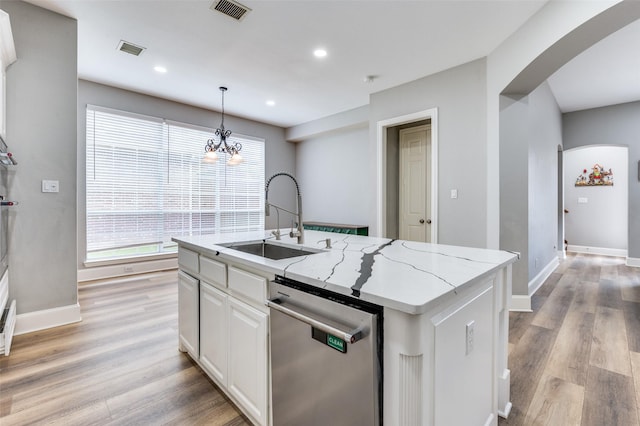 11722 Estacado Dr, Frisco, TX 75033 - kitchen featuring stainless steel dishwasher, arched walkways, light wood finished floors, white cabinetry, and light stone counters