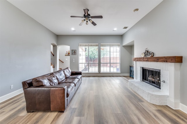 11722 Estacado Dr, Frisco, TX 75033 - living area with a brick fireplace, wood finished floors, a ceiling fan, arched walkways, and stairway