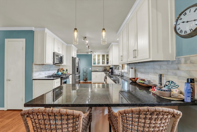 2113 Trinity Dr, Waco, TX 76710 - kitchen featuring stainless steel appliances, light wood-type flooring, backsplash, a peninsula, and white cabinets