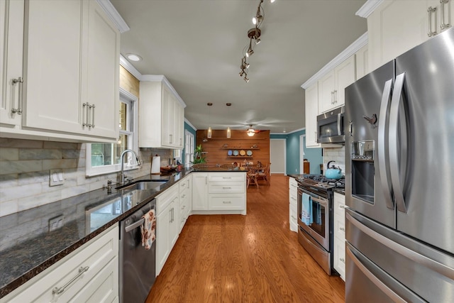 2113 Trinity Dr, Waco, TX 76710 - kitchen featuring stainless steel appliances, white cabinetry, light wood-style flooring, a peninsula, and backsplash