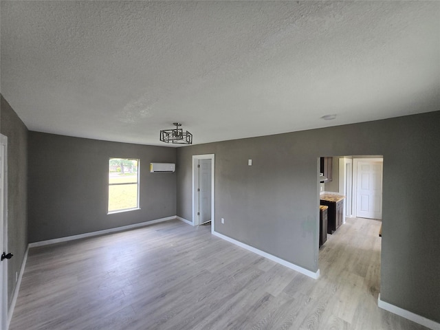 130 Jackson St N, Sulphur Springs, TX 75482 - unfurnished room featuring a textured ceiling, light wood-type flooring, a chandelier, and an AC wall unit
