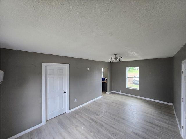 130 Jackson St N, Sulphur Springs, TX 75482 - empty room with a chandelier, a textured ceiling, and light wood finished floors