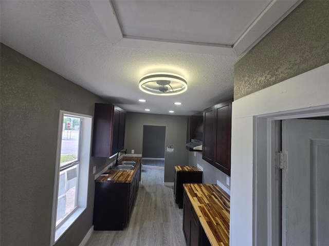 130 Jackson St N, Sulphur Springs, TX 75482 - kitchen with light wood-style flooring, a textured ceiling, wooden counters, under cabinet range hood, and recessed lighting
