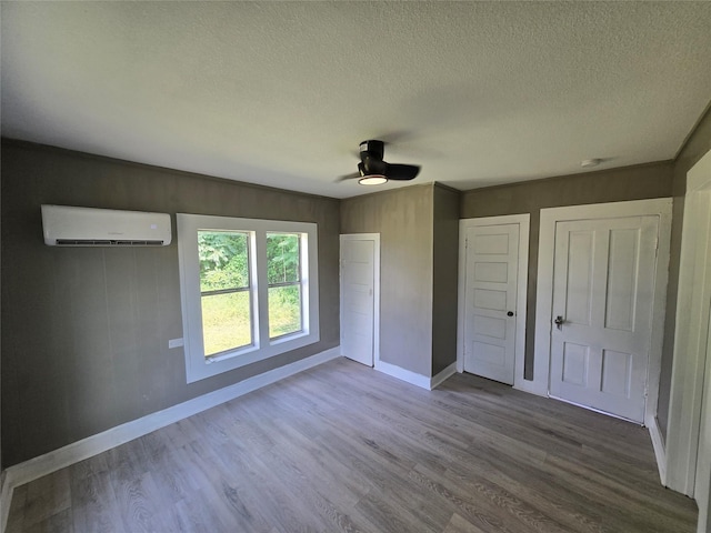 130 Jackson St N, Sulphur Springs, TX 75482 - unfurnished bedroom featuring an AC wall unit, a textured ceiling, wood finished floors, a ceiling fan, and two closets