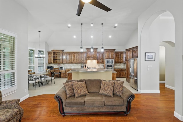 2428 Lilyfield Dr, Trophy Club, TX 76262 - living room with arched walkways, a ceiling fan, light wood-type flooring, a chandelier, and high vaulted ceiling