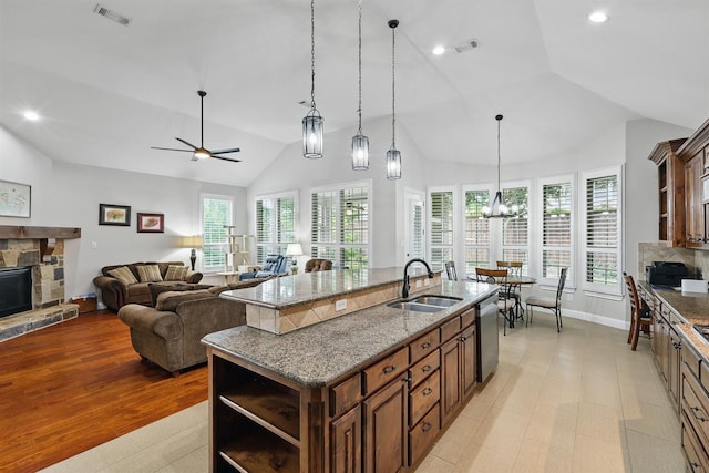 2428 Lilyfield Dr, Trophy Club, TX 76262 - kitchen with open shelves, lofted ceiling, a stone fireplace, dishwasher, and an island with sink