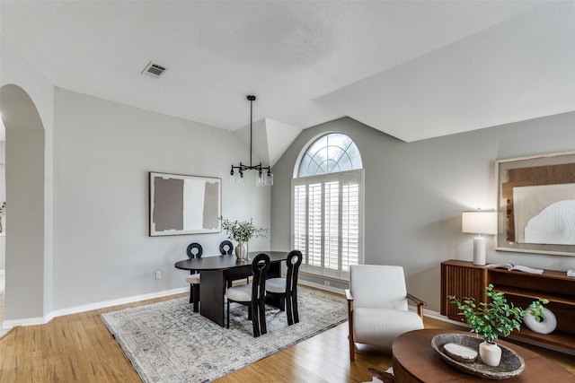 10715 Robincreek Ln, Frisco, TX 75035 - dining area featuring arched walkways, wood finished floors, lofted ceiling, and a chandelier