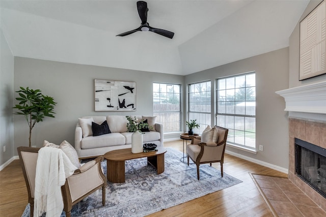 10715 Robincreek Ln, Frisco, TX 75035 - living room featuring lofted ceiling, a tiled fireplace, a ceiling fan, and wood finished floors